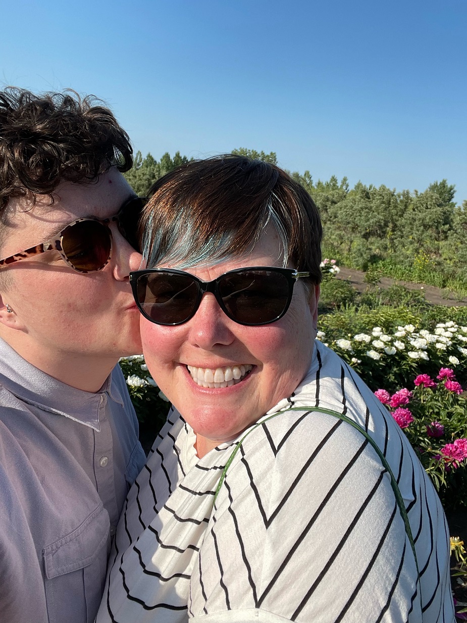 photo of katie kissing their wife viv in a field of peonies